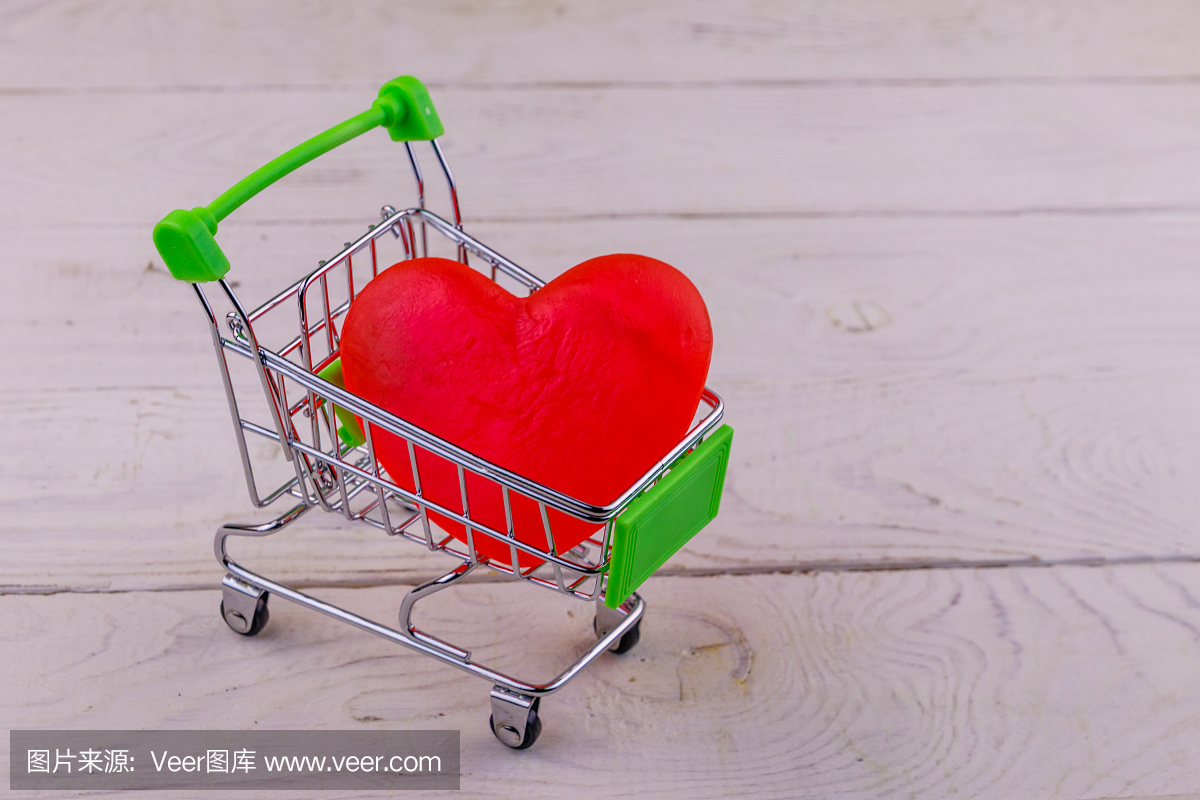 购物车与大红心在白色木制背景。情人节的概念